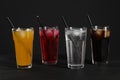 Glasses of different refreshing soda water with ice cubes and straws on black table Royalty Free Stock Photo