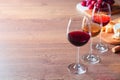 Glasses with different wines and appetizers on wooden table