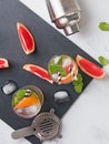 Glasses with drink, bar equipment and pieces of grapefruit on the black slate stone, top view. Royalty Free Stock Photo