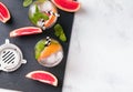 Glasses with drink, bar equipment and pieces of grapefruit on the black slate stone, top view. Royalty Free Stock Photo