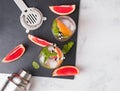Glasses with drink, bar equipment and pieces of grapefruit on the black slate stone, top view. Royalty Free Stock Photo