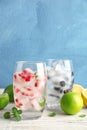 Glasses of drinks with fruit ice cubes on table against color background. Royalty Free Stock Photo