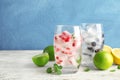 Glasses of drinks with fruit ice cubes on table against color background. Royalty Free Stock Photo