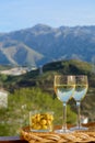 Glasses of dry white wine and spanish tapas olives in bowl with mountains peaks on background in sunny day Royalty Free Stock Photo