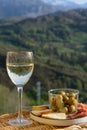 Glasses of dry white wine and spanish tapas olives in bowl with mountains peaks on background in sunny day Royalty Free Stock Photo