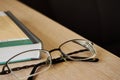 Glasses on the edge of the table next to the book close up with copy space Royalty Free Stock Photo