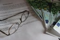 Glasses and 100 Euro bills put on agreement, close-up. Business contract evaluation and profitability concept Royalty Free Stock Photo