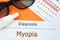 Glasses, eye drops and eye test chart is around inscription Diagnosis Myopia Nearsightedness. Concept photo for causes, diagnosi