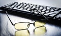 Glasses for eye protection near the keyboard Royalty Free Stock Photo