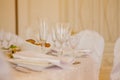 Glasses, flowers, fork, knife, napkin folded in a pyramid, served for dinner in restaurant with cozy interior. Wedding decorations Royalty Free Stock Photo