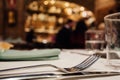 Glasses, fork, knife served for dinner in restaurant with cozy interior.Blurred people enjoying food Royalty Free Stock Photo