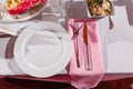 Glasses, forks, knives, napkins and a decorative flower on a white tablecloth table are served for dinner in a cozy restaurant. De Royalty Free Stock Photo