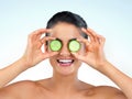 These glasses are so fresh and revitalising. Studio shot of a beautiful young woman posing with cucumbers against a blue