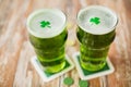 Glasses of green beer with shamrock and gold coins