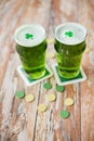 Glasses of green beer with shamrock and gold coins