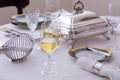 Glasses half filled with white wine on elegant table set with beautiful antique silver and porcelain dishes Royalty Free Stock Photo