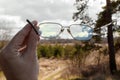 Glasses in hand against a forest background Royalty Free Stock Photo