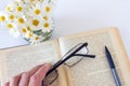 Glasses in hand on an old book open on white table background. Royalty Free Stock Photo