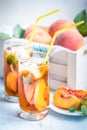 Glasses with homemade ice tea, peach flavored. Freshly cut peach slices for arrangement. White crate full with peaches in the back Royalty Free Stock Photo