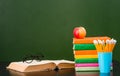 Glasses lying on the book near empty green chalkboard. Sample for text Royalty Free Stock Photo