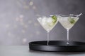 Glasses of martini with cucumber on tray against blurred lights Royalty Free Stock Photo