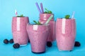 Glasses and mason jar tasty blackberry smoothie on blue background