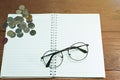 Glasses on notebook with coins. Concept saving Royalty Free Stock Photo