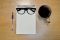 Glasses notebook pen and cup of coffee in wood table Royalty Free Stock Photo