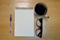 Glasses notebook pen and cup of coffee in wood table Royalty Free Stock Photo