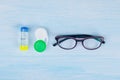 Glasses and objects for cleaning and storing contact lenses, to improve vision, on a blue background