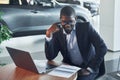 In glasses. Office worker is sitting in autosalon by table with laptop