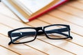 Glasses and open book on wooden table close Royalty Free Stock Photo