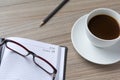 Glasses over a personal organizer and a cup of coffee on a desk