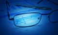 Glasses and pen on blue financial chart and graph, blue tone, success concept Royalty Free Stock Photo