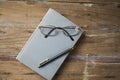 Glasses and a pen on a book on a wooden table Royalty Free Stock Photo