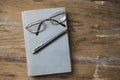 Glasses and a pen on a book on a wooden table Royalty Free Stock Photo