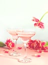 Glasses of pink cocktails with flowers and petals. Birthday party or Valentines day romatic couple concept.