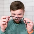 Glasses with raindrops in the hands of a man who looks at them with displeasure.