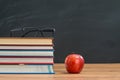 Glasses and red apple with Books on the Teacher`s School Desk