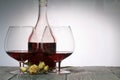 Glasses with red dry wine. Nearby is a bottle of wine and a bouquet of dried roses. Stand on wooden boards. Shot in backlight Royalty Free Stock Photo