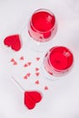 Glasses of red grape wine with red candies heart shape on the white background. Top view Royalty Free Stock Photo