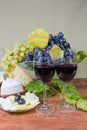 Glasses of red wine against blue grapes and various cheese Royalty Free Stock Photo