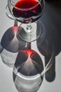 Glasses of red wine and bottle with shadows and reflections on a white textured surface. Royalty Free Stock Photo