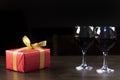 Glasses of red wine. Gift in a red package with a gold bow. St. Valentine`s Day. Love Royalty Free Stock Photo