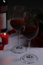 Glasses of red wine, rose flowers and burning candle on white table. Romantic atmosphere Royalty Free Stock Photo