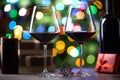Glasses of red wine on table with gift boxes and candle. Christmas lights in the background Royalty Free Stock Photo