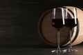 Glasses of red wine and wooden barrel on table against dark background Royalty Free Stock Photo