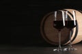 Glasses of red wine and wooden barrel on table against dark background Royalty Free Stock Photo