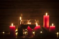 Glasses of red wine on a wooden table. Burning candles and decorations in the background. New Year or Christmas holiday. Valentine