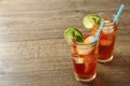 Glasses of refreshing iced tea on wooden table